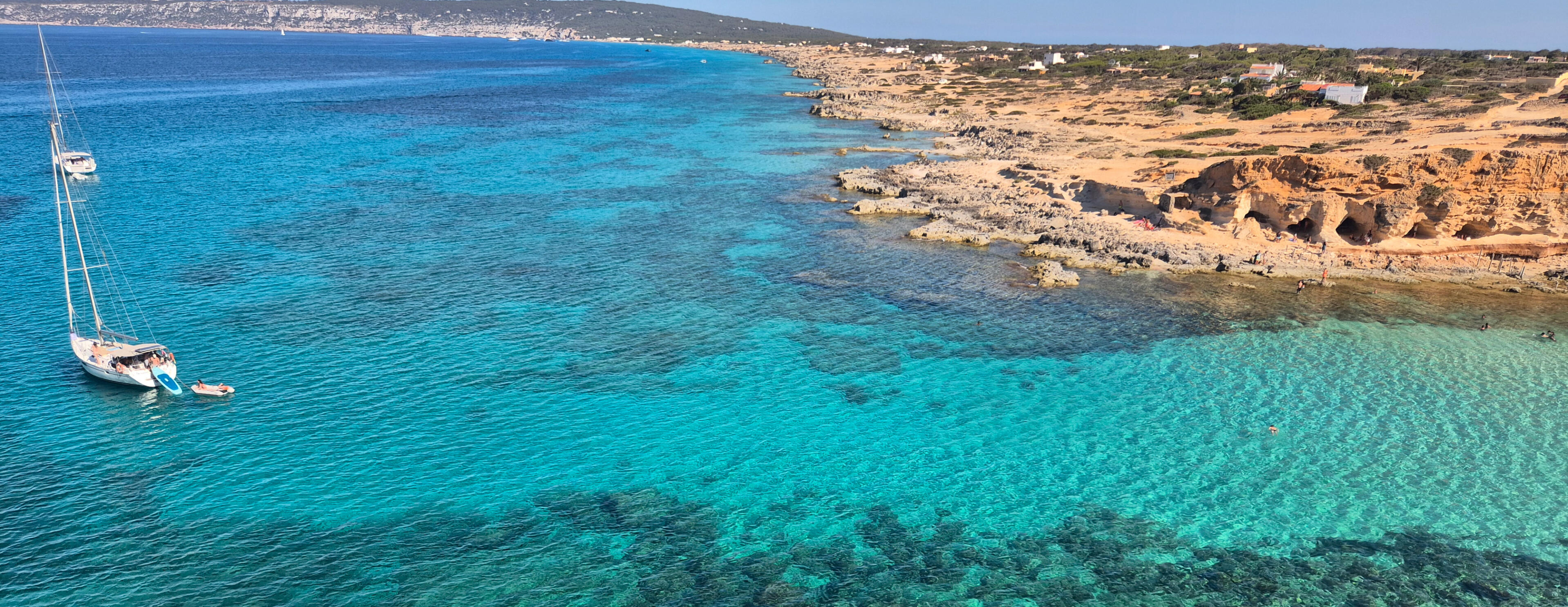 El velero Paradise fondeado en una cala de aguas turquesas en Formentera, ideal para un charter consciente.